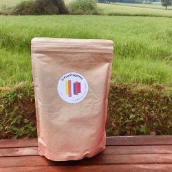 Dinkel Hafer Crunchy Packung auf einer Bank vor einem Feld