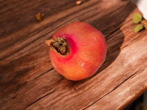 Leuchtend roter Granatapfel der Sorte Akko auf einem Holztisch